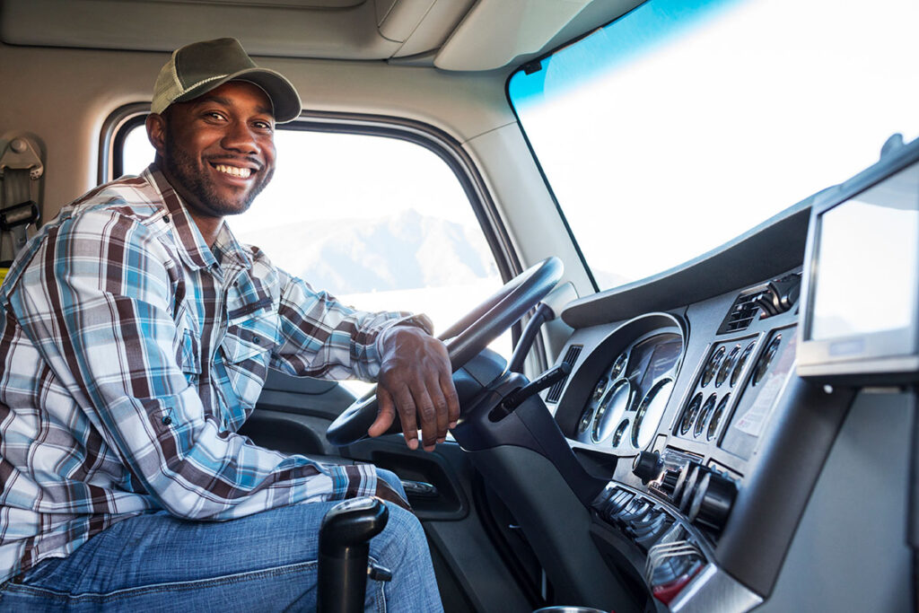 Truck driver in the cab of his truck smiling